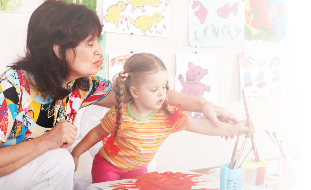 teacher teaching the little girl to paint